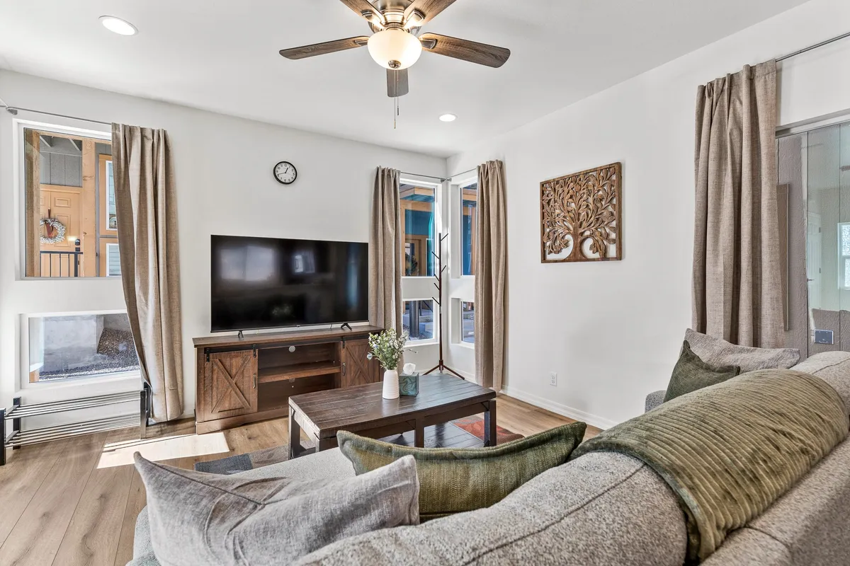 A cozy living room setup featuring a comfortable sofa, coffee table, television, and artistic wall décor. The space is designed for relaxation, conversation, and social interactions, with soft lighting giving it a welcoming ambiance.